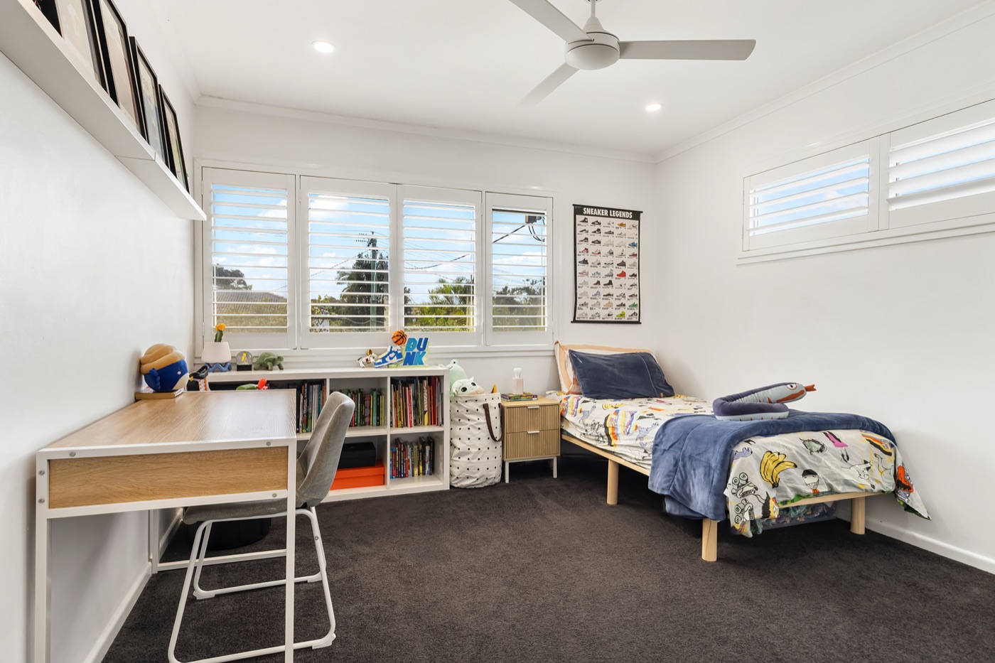 Fourth bedroom with a single bed, study desk and bookshelf under louvred windows