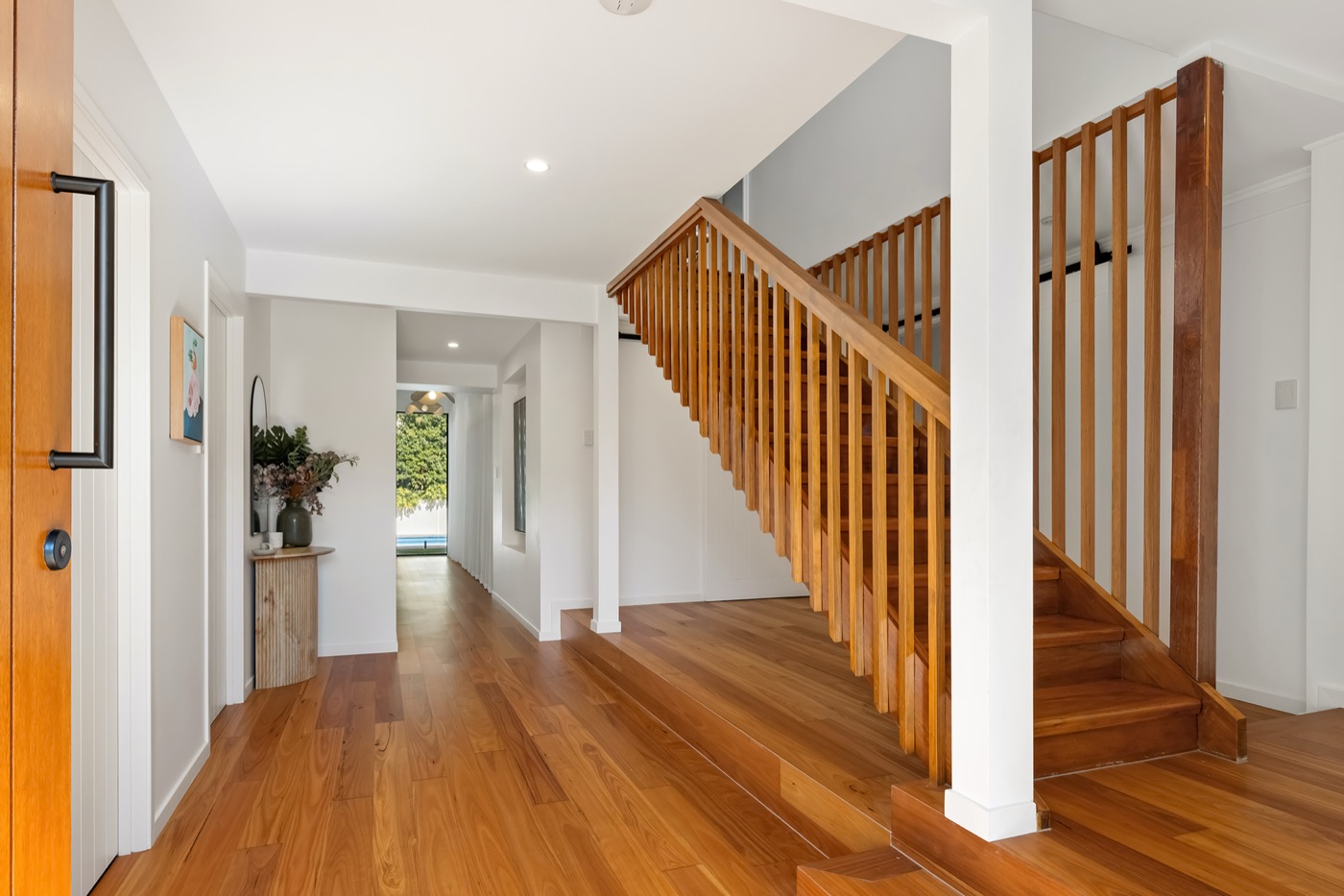 Entry hall with timber floors looking through the length of the house to the pool beyond