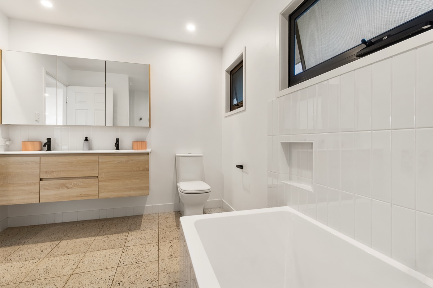 Family bathroom with a built-in bath, twin basins on a timber vanity and terrazzo floor tiles