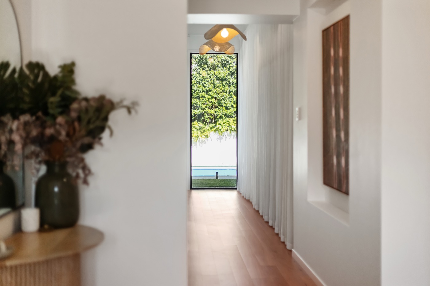 Hallway looking through a full-height window to the lawn and pool