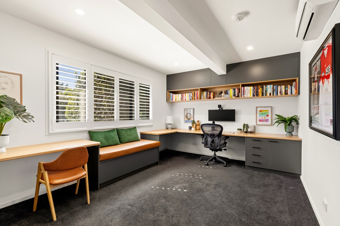 Purpose-built home office with custom timber desks around three walls, upper bookshelves and a built-in bench seat