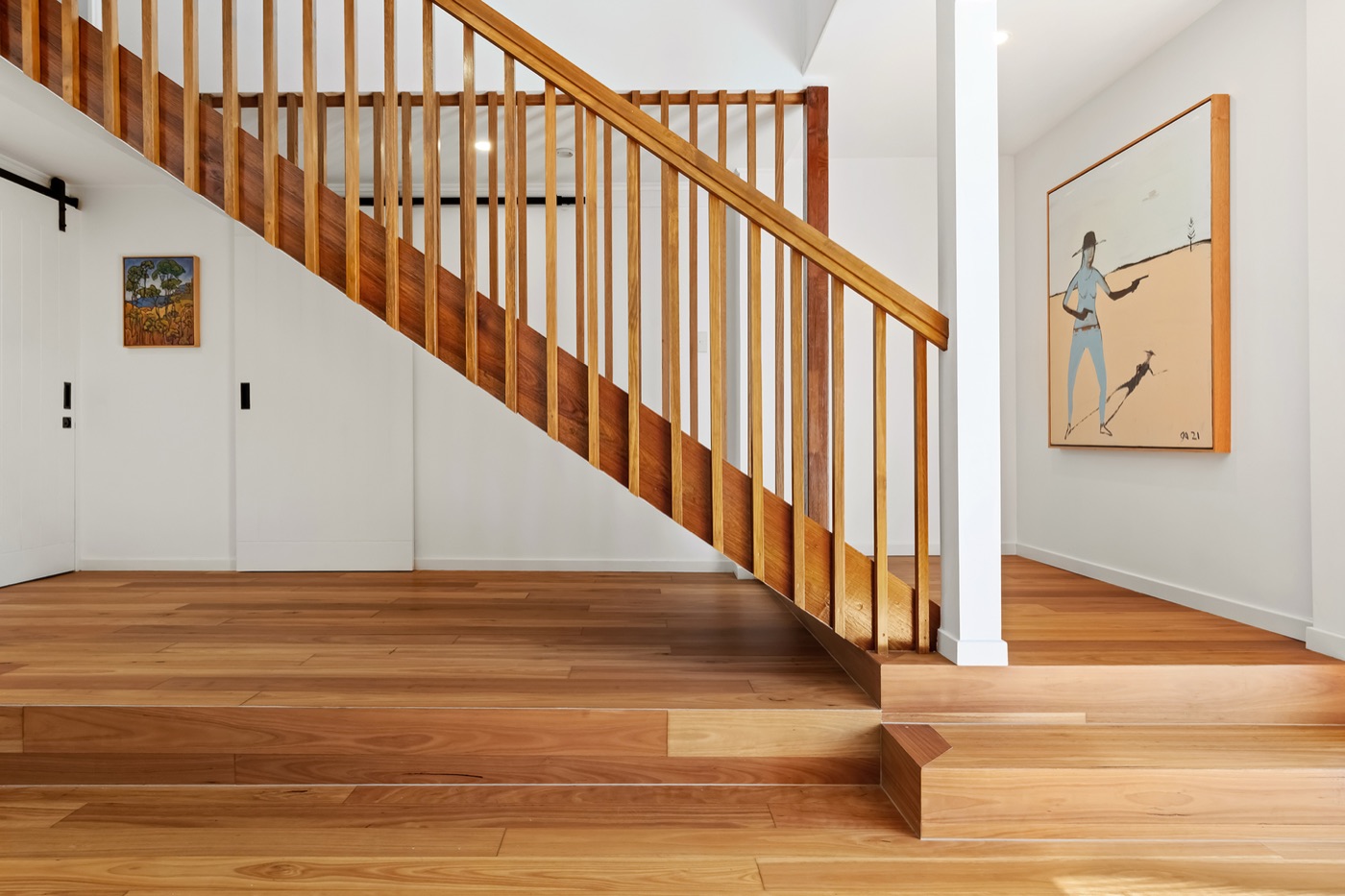 Spotted-gum timber staircase with slatted timber balustrade rising from the living area