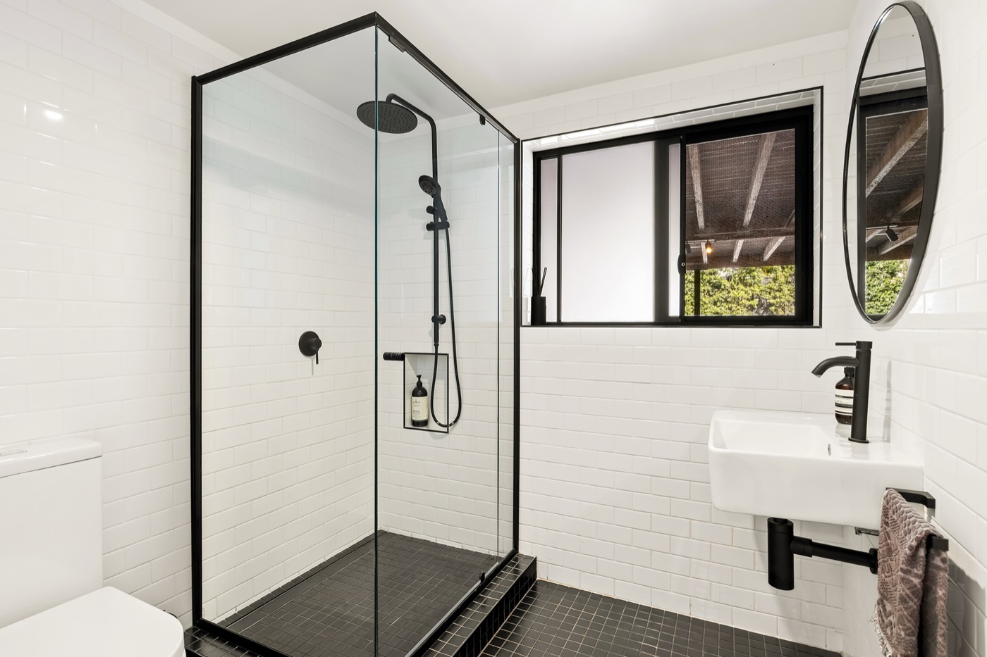 Third bathroom with a glass shower, wall-hung basin and white subway tiles